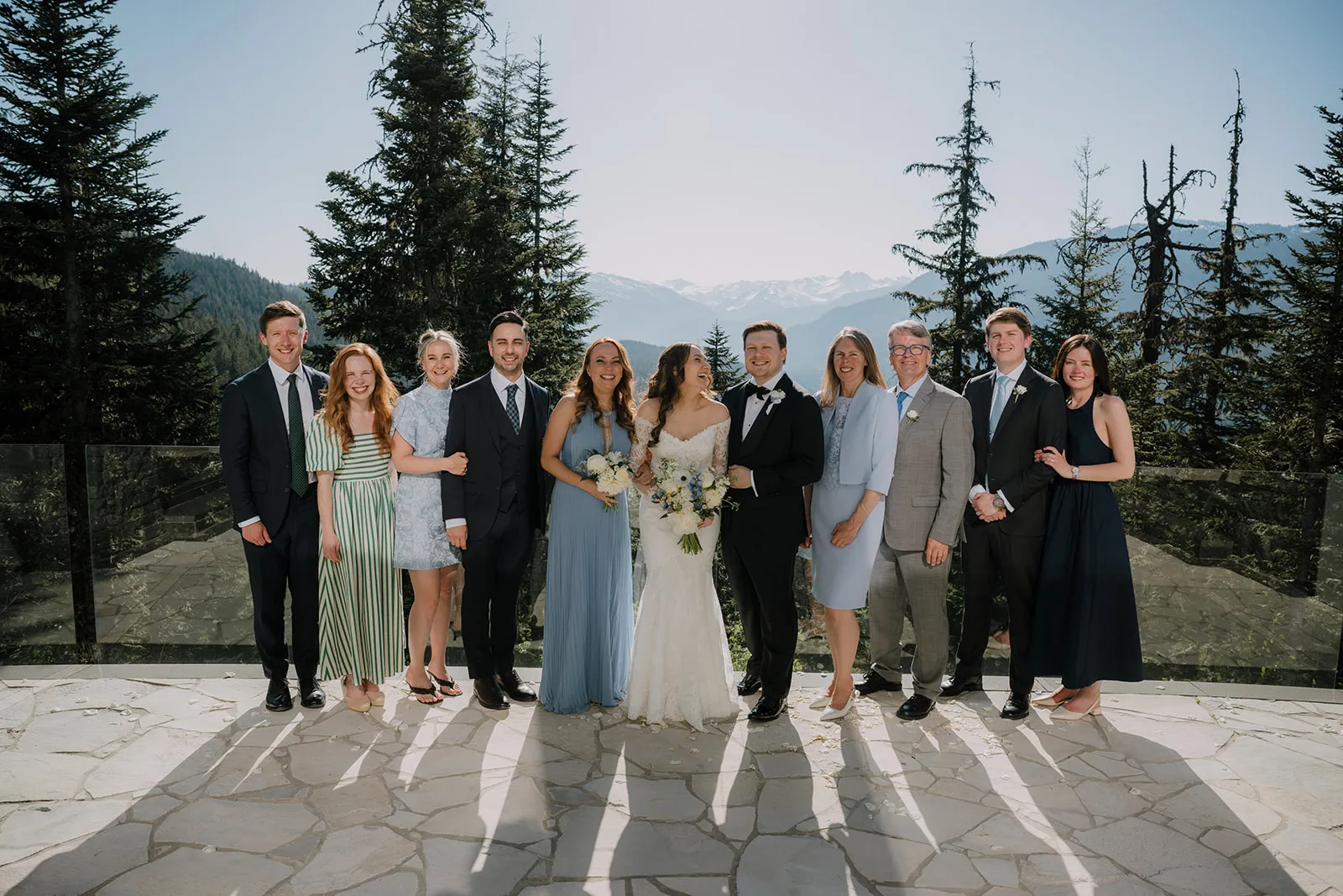 The whole gang Group photo of the whole party on a stone terrace, with snow-capped mountains and pine forest behind them